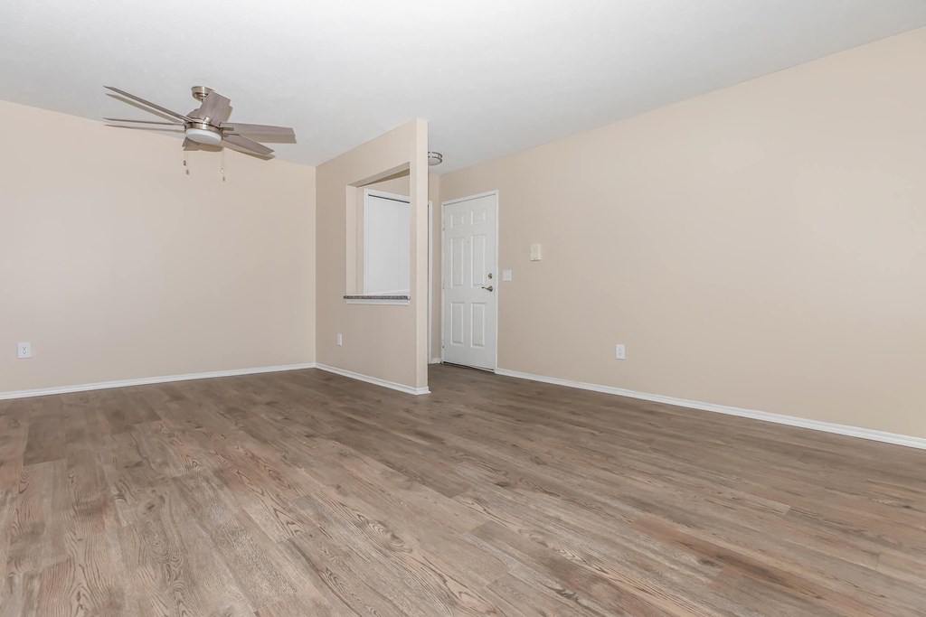 an empty living room with a ceiling fan and wood floors