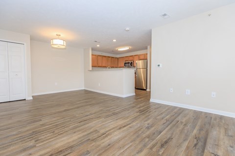 A kitchen area with a wooden floor and a refrigerator.