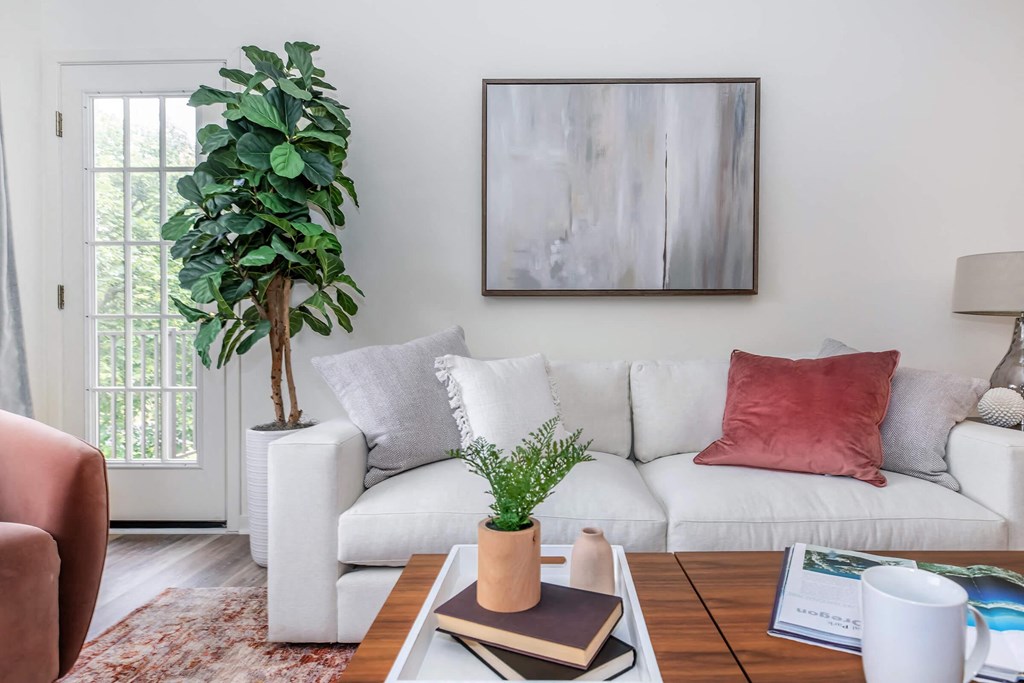a living room with a white couch and a table with a plant