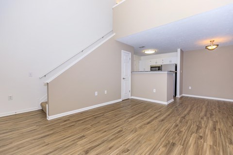 the living room and kitchen of an empty house with wood flooring
