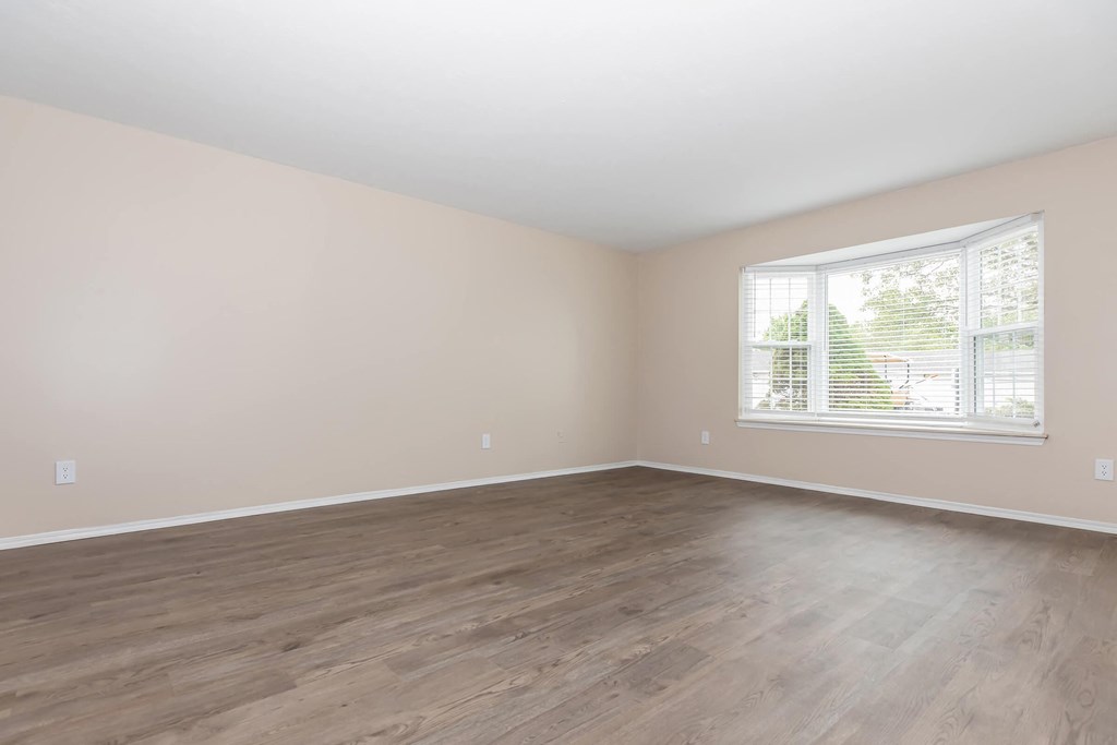 an empty living room with wood floors and a window