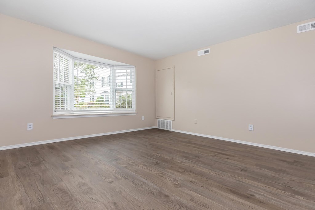 an empty room with wood floors and a window
