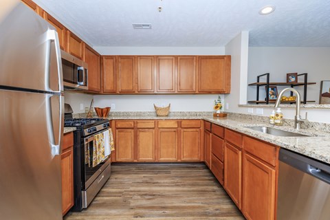 A kitchen with wooden cabinets and a stainless steel refrigerator.