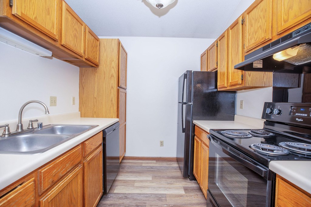 a kitchen with wooden cabinets and a black stove and refrigerator