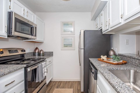 A kitchen with a black refrigerator and white cabinets.
