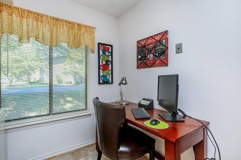 a home office with a computer desk and a window