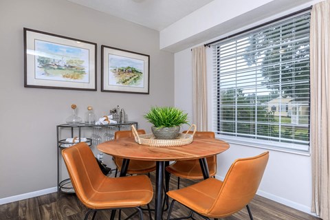 A dining room with a round table and orange chairs.