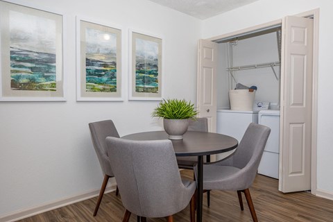 A dining room with a table and chairs and a potted plant.