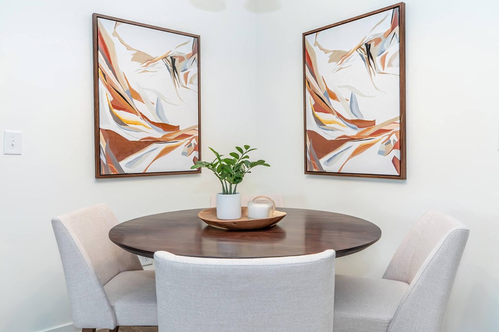 a dining room with two paintings on the wall and a table with chairs