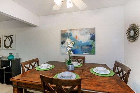 a dining room with a wooden table and a painting on the wall