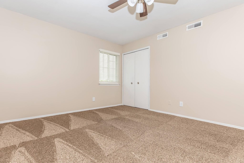 a living room with carpet and a ceiling fan