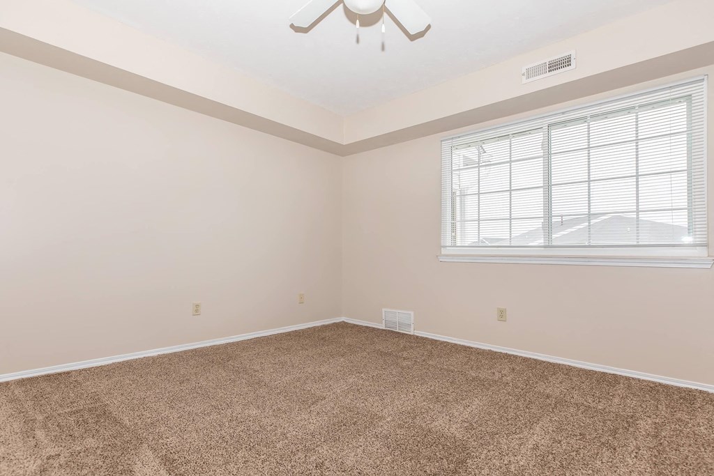 an empty room with a window and a ceiling fan