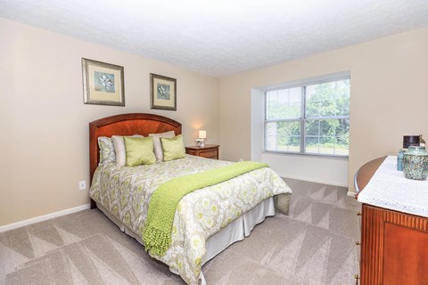 A bedroom with a bed, nightstand, and two pictures on the wall.