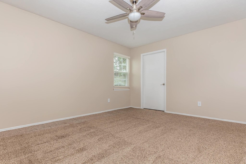 an empty living room with a ceiling fan