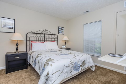 A bedroom with a bed, nightstands, and a window.