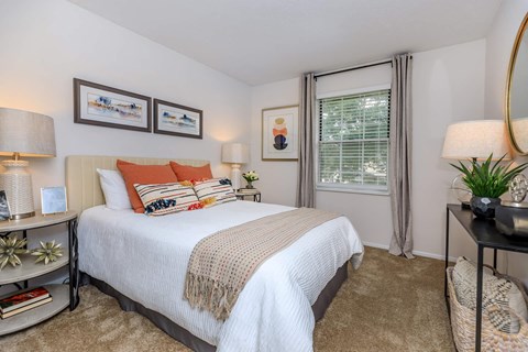A bedroom with a large bed and a window with curtains.