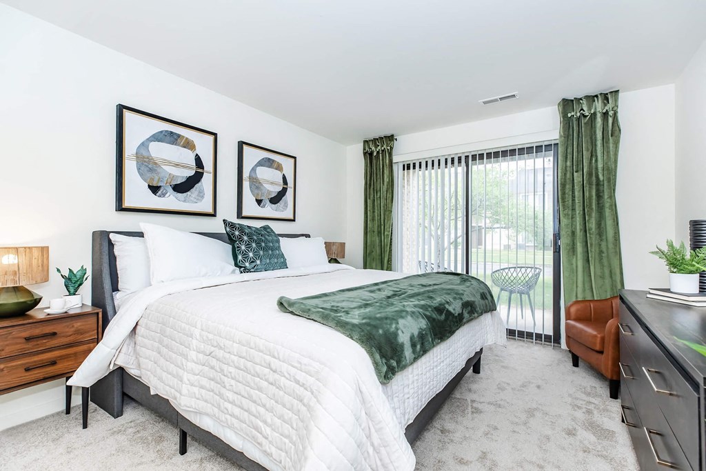 a bedroom with a bed and a sliding glass door to a balcony