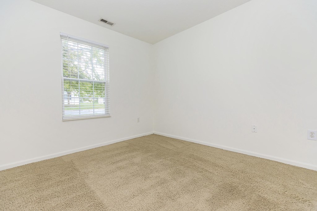 an empty room with carpet and a window