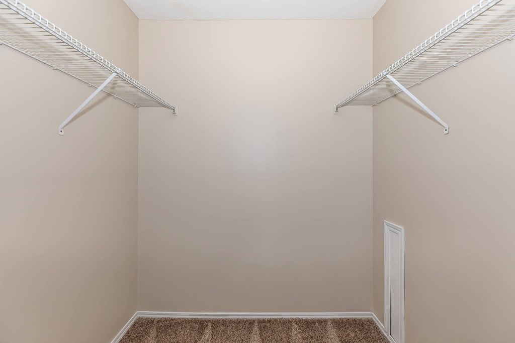 a walk in closet with two hanging racks on the wall