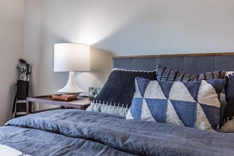 a bedroom with a bed with pillows and a lamp