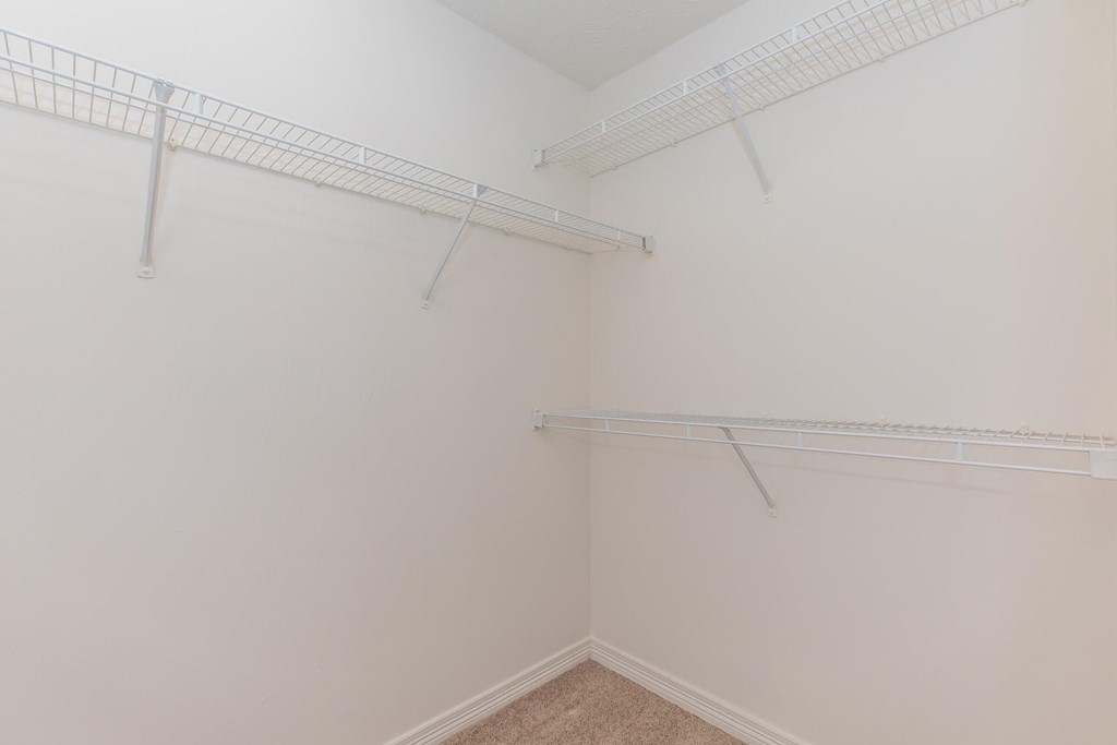 a white closet with two shelves on the wall and a window