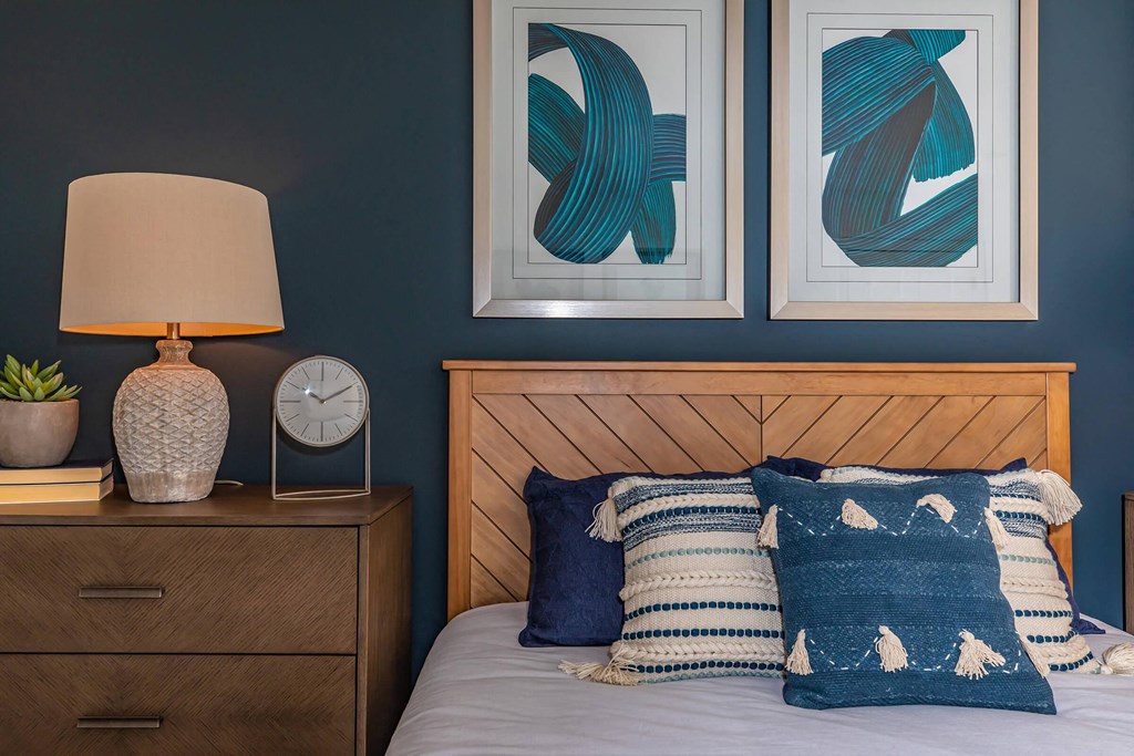a bedroom with a bed with blue and white pillows and paintings on the wall