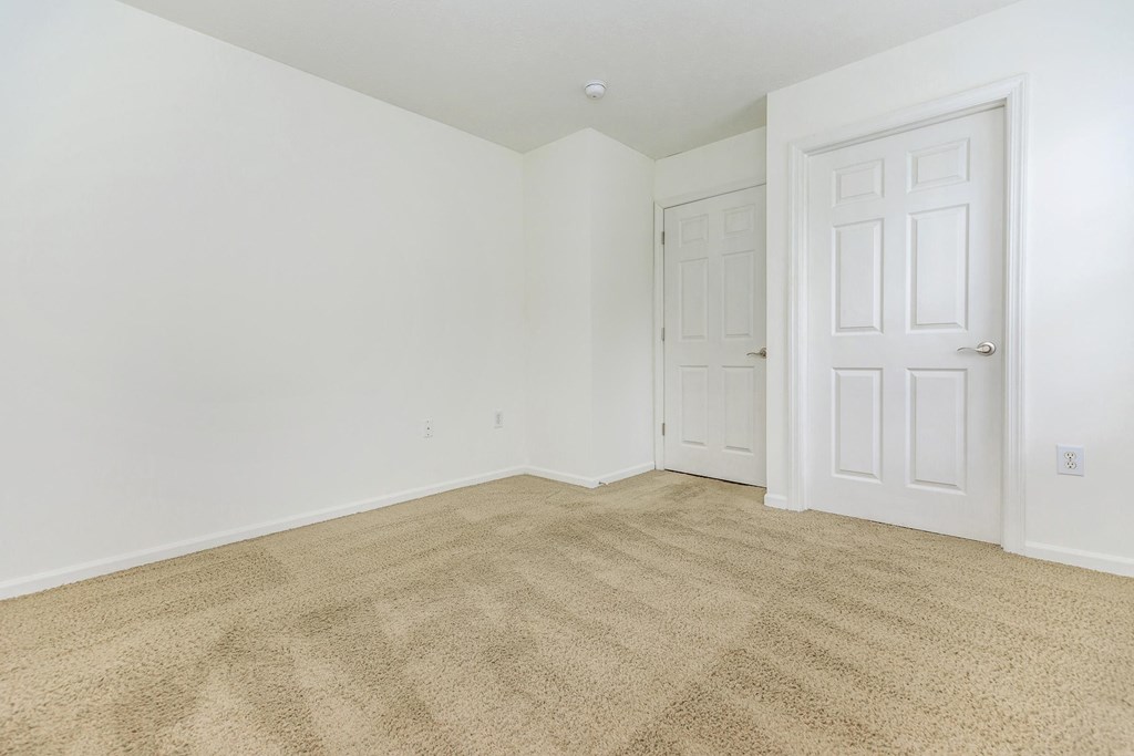 a bedroom with white walls and carpet and a white door