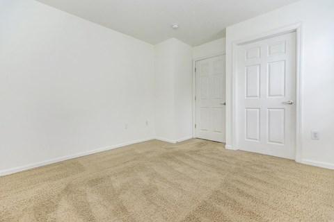 a bedroom with white walls and carpet and a white door