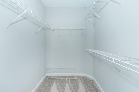 the walk in closet of a bedroom in an empty room with white walls