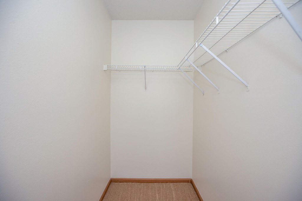 a walk in closet with white walls and a white rack on the wall