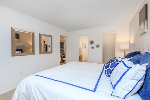 a bedroom with a large bed and three mirrors on the wall