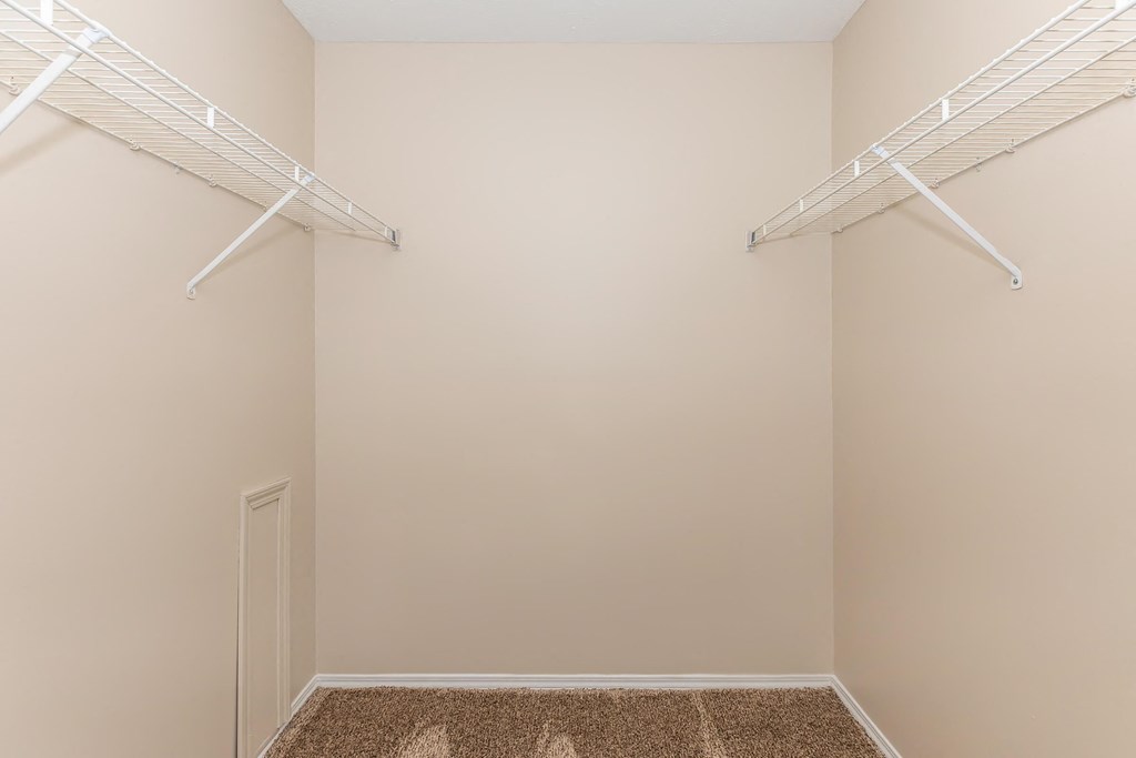 a closet in a bedroom with two hanging racks on the wall