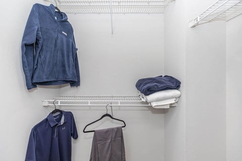 a walk in closet with jackets and shirts and a rack with towels