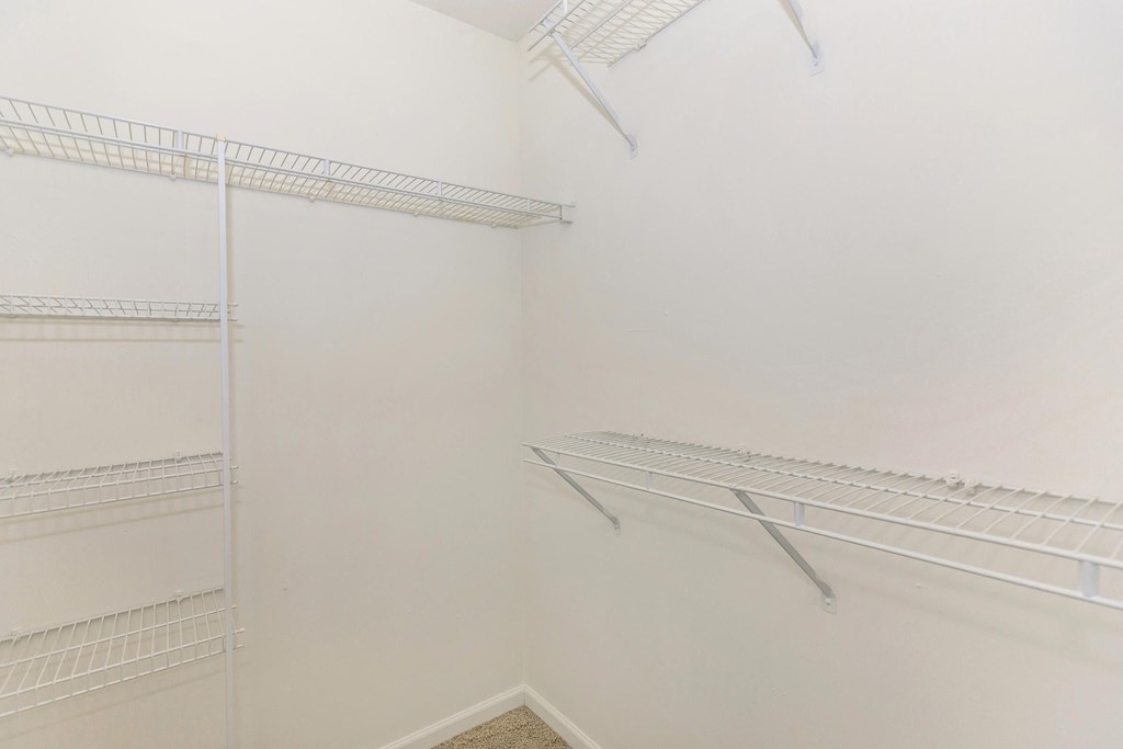 a walk in closet with white walls and metal shelves