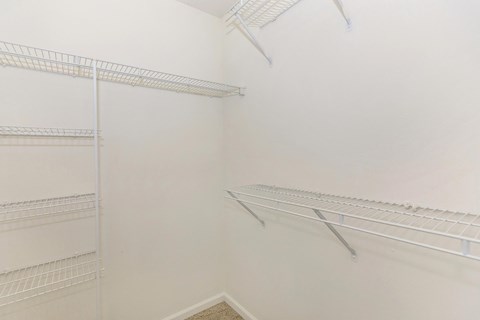 a walk in closet with white walls and metal shelves