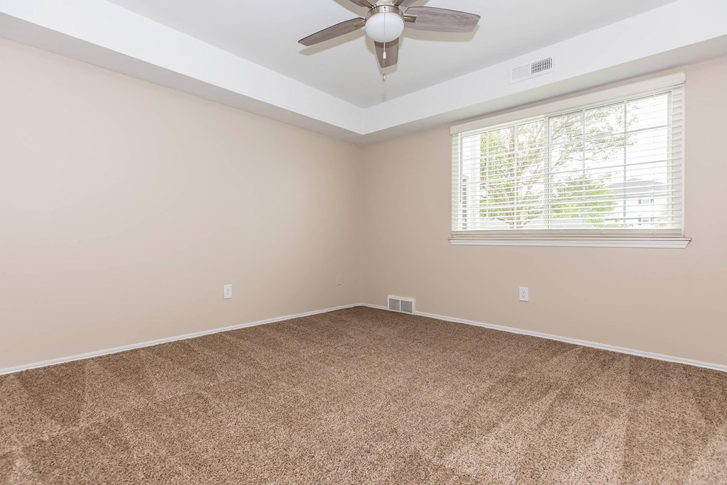 an empty living room with a ceiling fan and a window