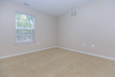 A room with a window and carpeted floor.