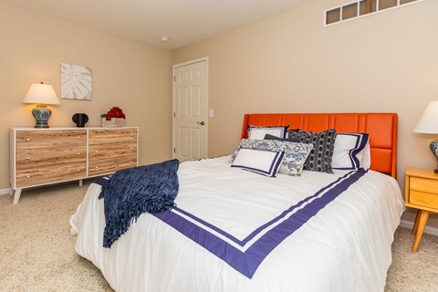 A bedroom with a white bed and a wooden dresser.