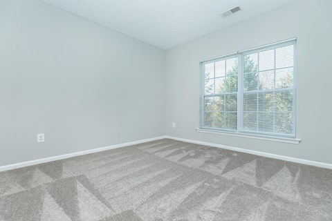 an empty bedroom with a large window and