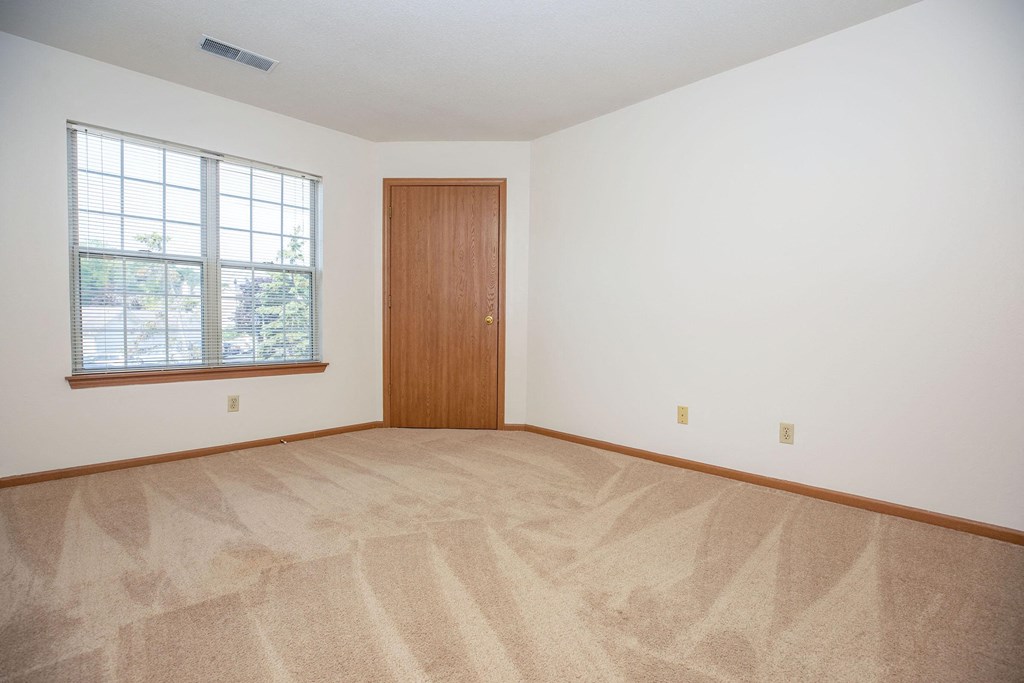 an empty living room with carpet and a door