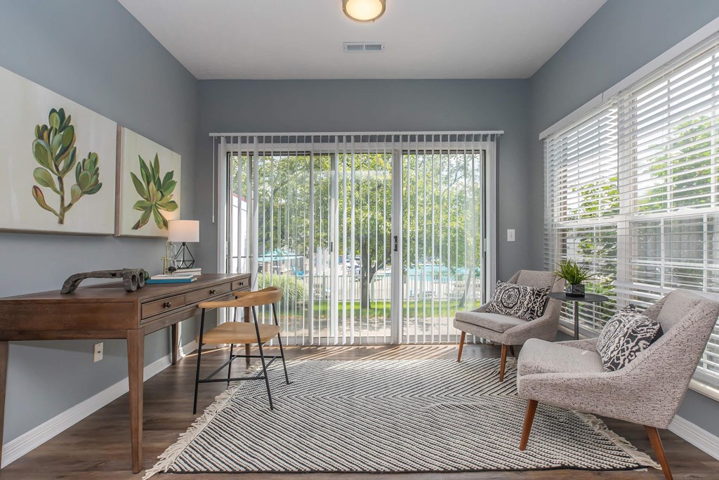 a living room with a desk and a sliding glass door