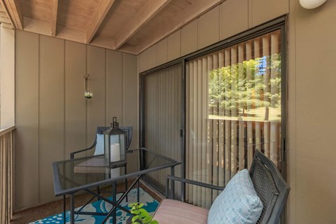 a balcony with a glass table and chairs and a sliding glass door