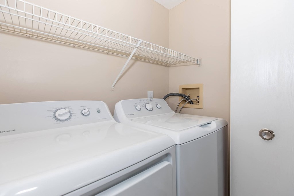a white washer and dryer in a laundry room with a shelf above it