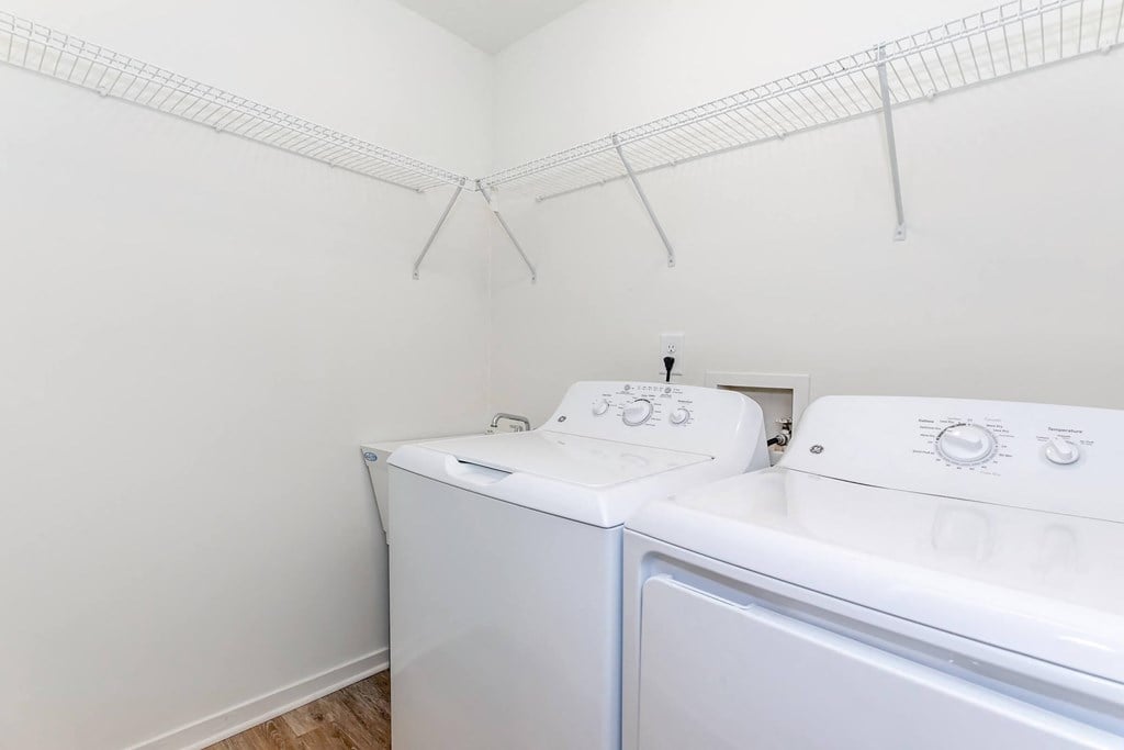 a white laundry room with two washes and a dryer