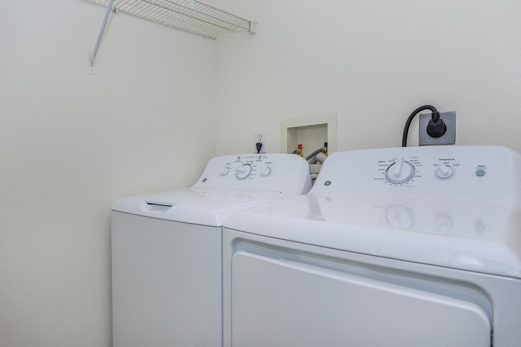 a white laundry room with two washes and a dryer