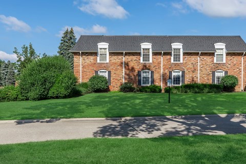 a red brick house with a green lawn in front of it