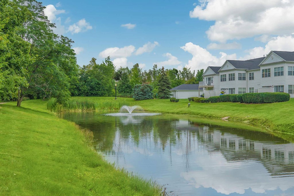 a pond in front of a house with a fountain