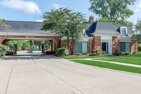 the front of a brick house with an archway over the driveway