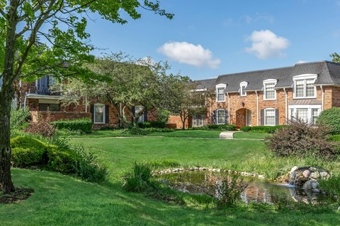 a large brick building with a pond in front of it