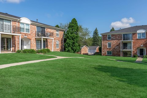 a green lawn in front of a brick apartment building